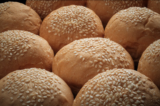 many baked sesame topping burger breads lay on oven tray waiting for cooking, shot with shallow focusing and tilted lens effect for background wallpaper