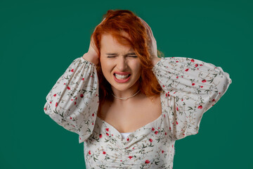Irritated Young Red-haired Woman Covering Ears Ignoring On Green. Noise, Shouts.