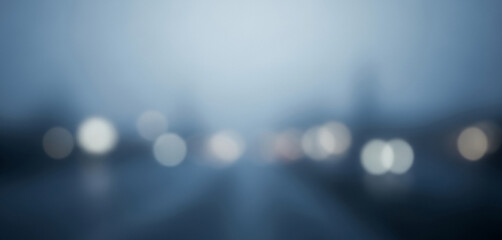 Blurred city lights in fog or rain abstract background with blue tint, creating a moody and cinematic feel perfect for urban posters, night-themed branding, or ambient visual stories.