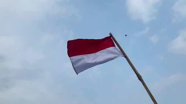 Indonesian red and white flag waving against a blue sky during Indonesia's Independence Day celebration