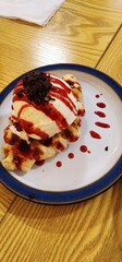 Delicious Waffle Dessert Topped With Ice Cream and Strawberry Syrup