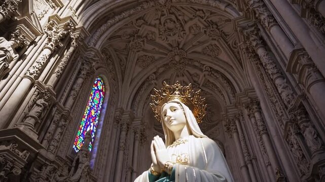 Crowned religious statue with folded hands in European basilica sanctuary