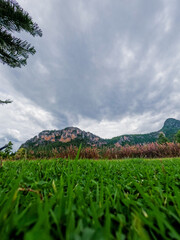 Low-Angle View of Mountain with Green Grass and Overcast Sky