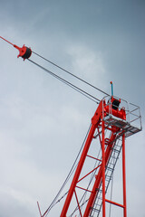 Bright Red Crane Upper Structure with Cables and Operator Cabin Against Overcast Sky