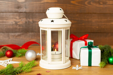Beige christmas lantern with decorations on wooden table