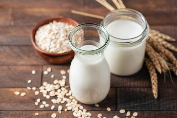 Non dairy oat milk in bottle on wooden table background. Healthy alternative milk choice