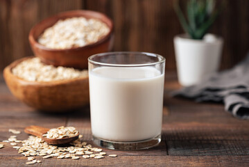 Oat milk in glass on wooden table, rustic style. Healthy vegan non dairy alternative milk
