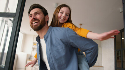 Smiling Caucasian daughter dad male daddy having fun guy girl dancing together enjoying weekend playing at home little kid piggyback ride happy father man carry child family laughing leisure childcare
