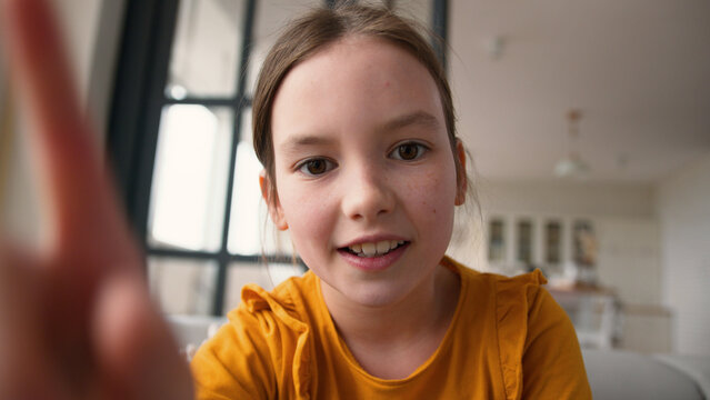 Webcam display point of view POV screen modern happy Caucasian little child girl daughter scrolling screen mobile phone smartphone tech kid rejoice touchscreen at home smiling schoolgirl typing gadget