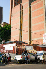 Urban Street Life Scene with Community Gathering in Front of Brick Apartment Building. Authentic urban street life scene featuring a group of people gathered around a pickup truck and taxi © pploylp