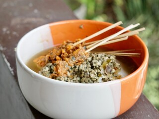 Authentic Lontong Kupang and Sate Kerang. A traditional clam soup with rice cakes in savory shrimp paste broth. Famous Indonesian street food specialty from Sidoarjo, East Java