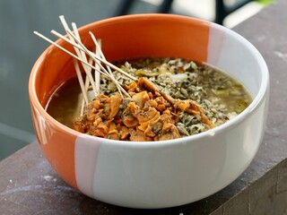 Authentic Lontong Kupang and Sate Kerang. A traditional clam soup with rice cakes in savory shrimp paste broth. Famous Indonesian street food specialty from Sidoarjo, East Java