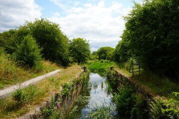 Obraz premium Scenic view of an overgrown canal lock and countryside pathway in summer near Codnor, Derbyshire, England