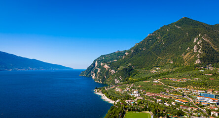 Obraz premium Aerial view of Limone sul Garda, a colorful lakeside town in Italy nestled between Lake Garda and steep mountains under a bright blue sky