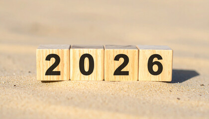 Number 2026 on wooden cubes, sand surface. New year, planning, vacation.