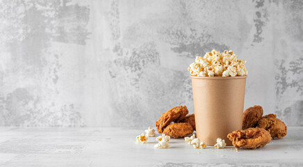 Paper cup filled with popcorn and surrounded by pastries on a table