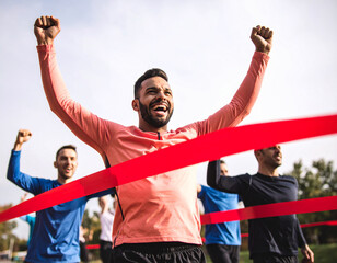Triumphant athlete celebrates victory crossing the finish line with arms raised high in the air