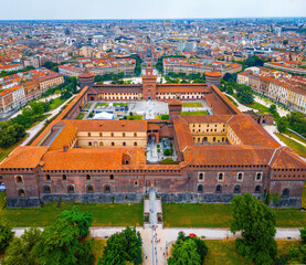 Historic Sforza Castle tower in Milan with medieval brickwork, large clock, and decorative details under a partly cloudy sky