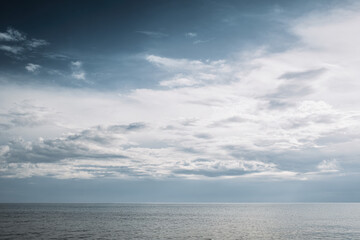 Obraz premium Peaceful Ocean Seascape with Dramatic Clouds and Calm Blue Water Reflecting Sky at Horizon