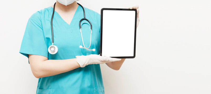 Masked healthcare worker in scrubs and gloves showing a black-screen tablet, suitable for copy space, medical interface, or app mockup