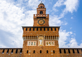 Historic Sforza Castle tower in Milan with medieval brickwork, large clock, and decorative details...