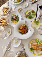 Luxurious dining table set with multiple courses of gourmet food including salmon, shrimp, escargot, and various appetizers, perfect for fine dining or catering designs