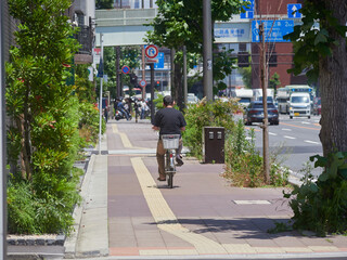 夏の京都の市街で歩く人々と自転車を乗る男性の姿
