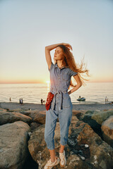 Lifestyle woman in modern boho-western denim street style posing confidently at sunset by the rocky...