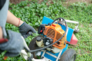 gardener pulling lawnmower starter cord, beginning the task of cutting the well-kept lawn