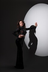 Girl in long black dress standing near circle in studio