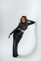 A girl in a long black dress on a white background, she has bright makeup