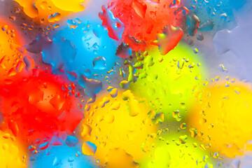 Abstract macro of water drops in vibrant red, yellow, blue, and green colors on a smooth surface,...