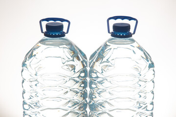 A pair of clear plastic water bottles with blue lids, featuring a wavy texture, set against a white...