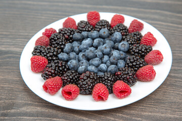 raspberries, blueberries and blackberries on a white plate. Vitamin and Diet Food