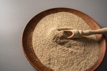 Natural psyllium husk powder displayed in a wooden bowl with a scoop ready for healthy dietary use