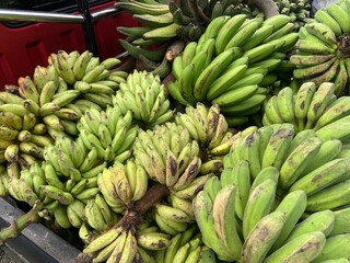 Piles of unripe bananas at the traditional market, green banana, asian market, tropical fruit market.