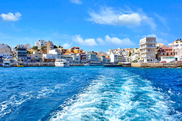 Fototapeta premium Waterfront buildings along Agios Nikolaos harbor, a coastal city on the island of Crete in Greece. 