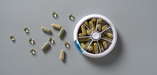 Multicolored dietary supplements scattered around a weekly pill organizer in a contemporary setting capturing wellness and health routines