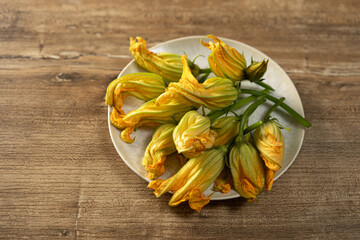 Colorful squash blossoms arranged beautifully on a white plate ready for culinary creativity in a rustic kitchen setting