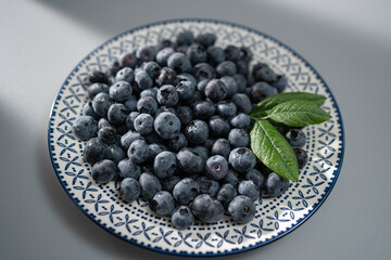 Freshly picked blueberries arranged artfully on a decorative plate with green leaves, showcasing vibrant colors and textures in a cozy kitchen setting