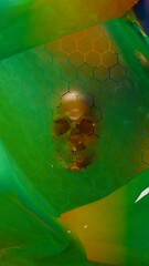 Human skull visible through hexagon grid with green liquid surface background