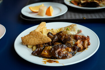A well-presented plate containing assorted food items including fried fish, fries, and vegetables
