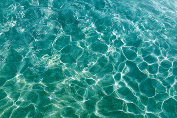 Obraz premium Clear, turquoise water with rippling patterns. The sunlight dances across the surface, creating beautiful reflections. A close-up shot emphasizes the clarity and purity of the water
