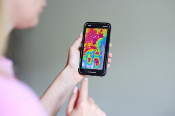 Close-up of hand holding smartphone with colorful weather radar, storm tracking, severe weather alert.