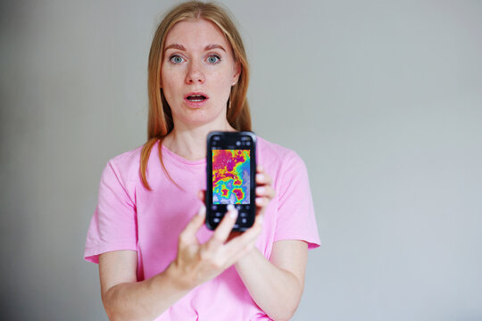 Scared woman checking severe storm alert on phone, climate crisis, mobile forecast, danger warning