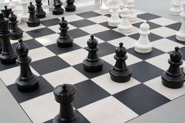 large chess pieces on a checkered game board in bright modern setting