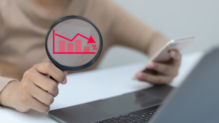Hand holding a magnifying glass with a red falling bar chart icon, analyzing financial crisis,...