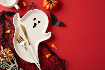 Festive Halloween table decor with a ghost plate, themed accessories, and a spooky red surface