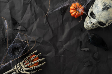 Atmospheric Halloween scene featuring a skull, skeleton hand, and other spooky elements on dark...