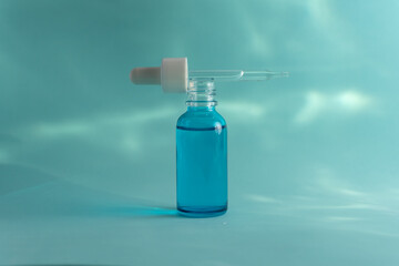 Botella azul con el gotero de forma horizontal sobre la boca de la botella en fondo acuático 